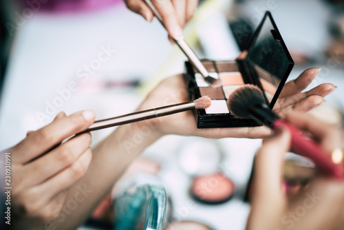 Women doing makeup with brush and cosmetic