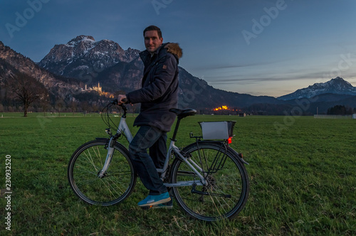 Das Schloß Neuschwanstein als Ausflugsziel mit dem Rad, ein Mann posiert auf dem Fahrrad vor dem berühmten Schloß im Allgäu, dem Süden von Bayern