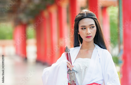 Beautiful Chinese woman with a traditional suit with a sharp sword in her hands, Beautiful and belligerent face, Young woman with a samurai bushido katana sword