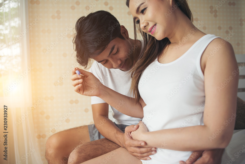 Happy couple smiling after find out positive pregnancy test in bedroom Happy couple smiling after find out positive pregnancy test in bedroom