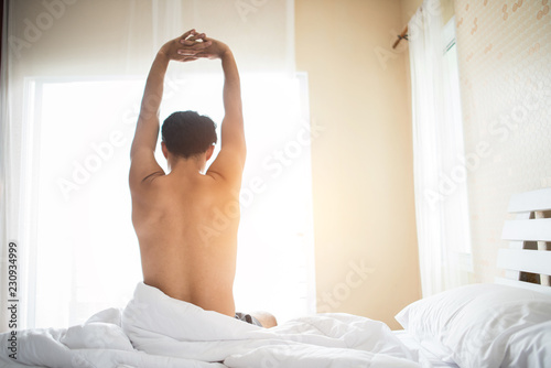 Handsome man wake up and raising hand on the ben in the morning