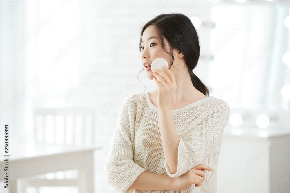 Joyful pretty Asian woman applying transparent powder on her fresh clear skin Joyful pretty Asian woman applying transparent powder on her fresh clear skin