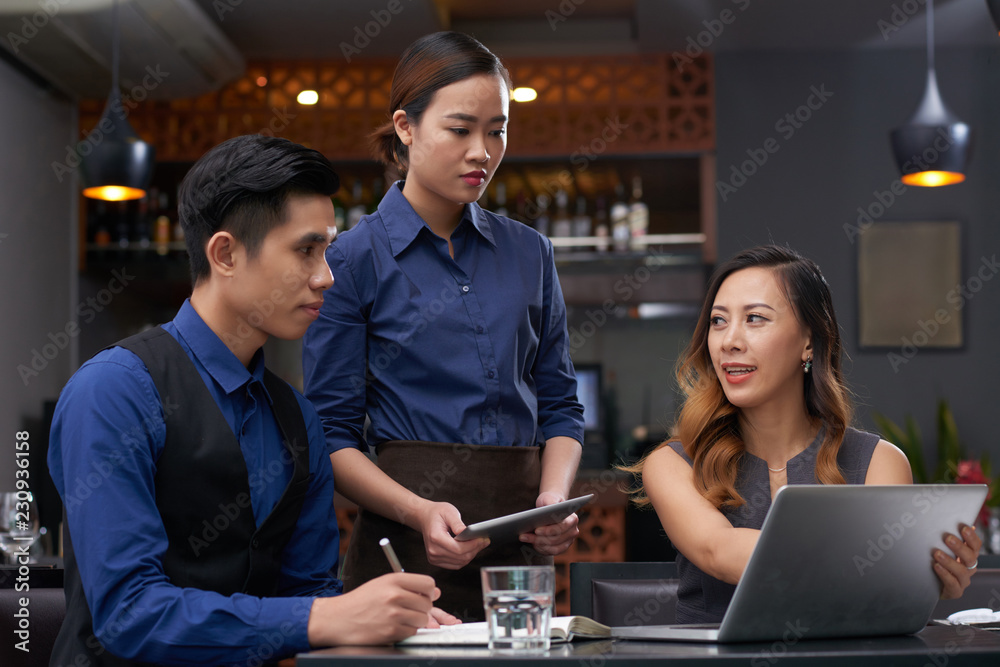 Restaurant owner explaining new strategy to barman and waitress Restaurant owner explaining new strategy to barman and waitress