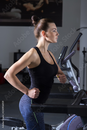 Young woman doing cardio exercises, running on treadmills in the gym