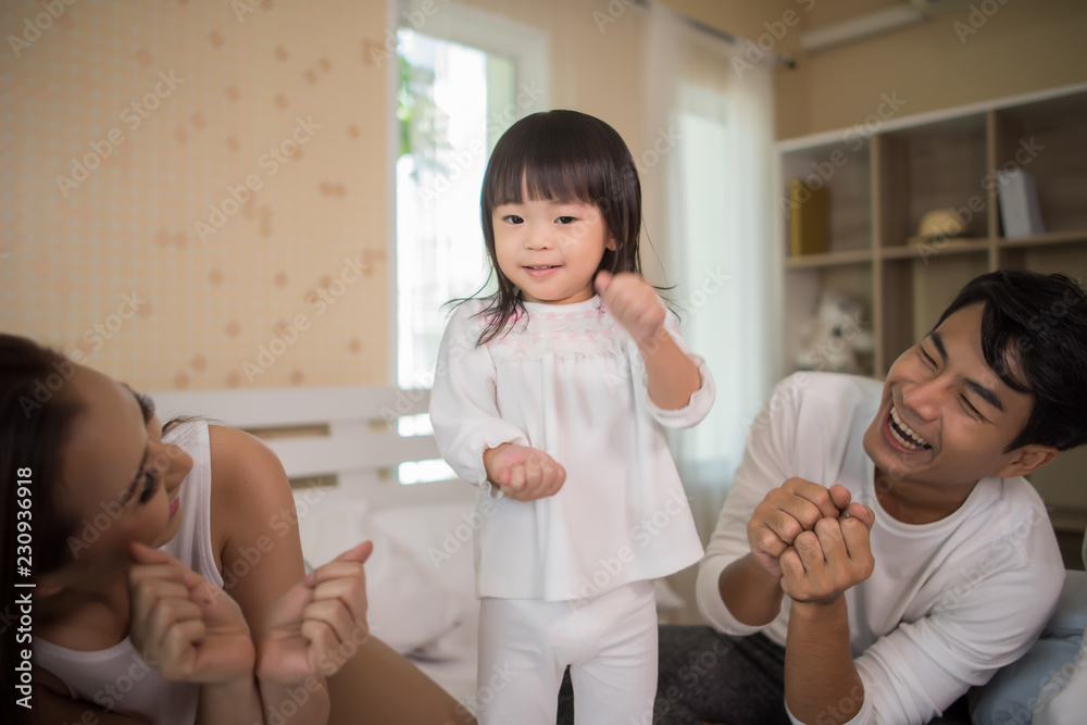 Happy child with parents playing in the bed at home