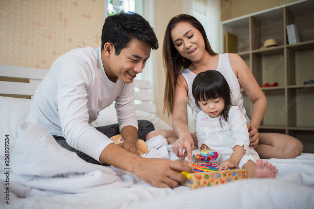 Happy child with parents playing in the bed at home Happy child with parents playing in the bed at home