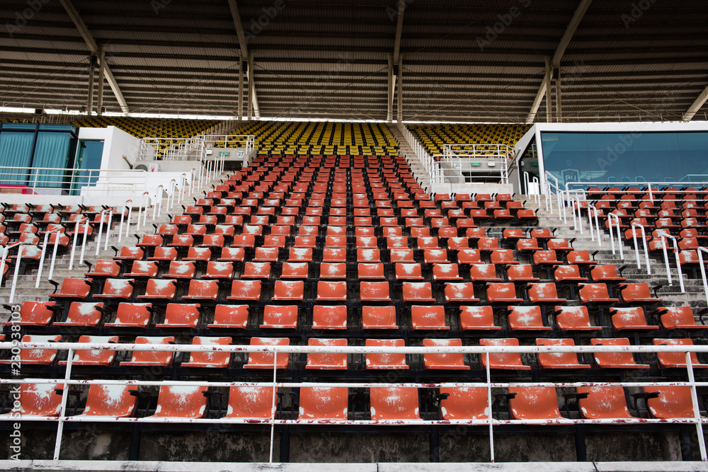Naklejka premium Red Empty and old plastic seats in the stadium.