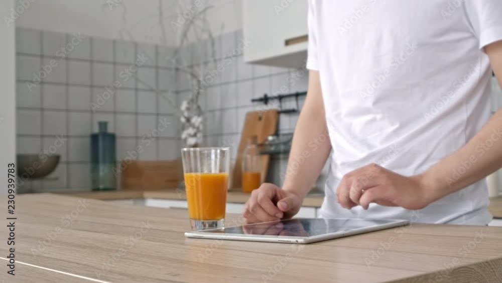 technology, home, drinks and lifestyle concept - close up of man with tablet pc computer and cup of orange juice at home. technology, home, drinks and lifestyle concept - close up of man with tablet pc computer and cup of orange juice at home.