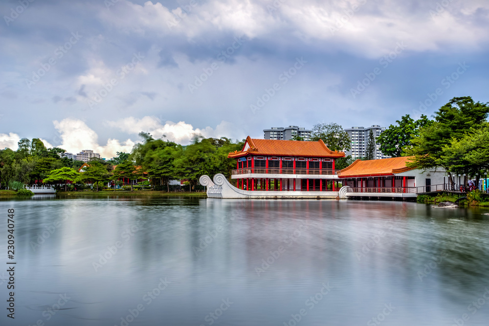Yao-Yueh Fang Stone boat structure in a pound in Chinese Singapore garden with blue cloudish and reflection