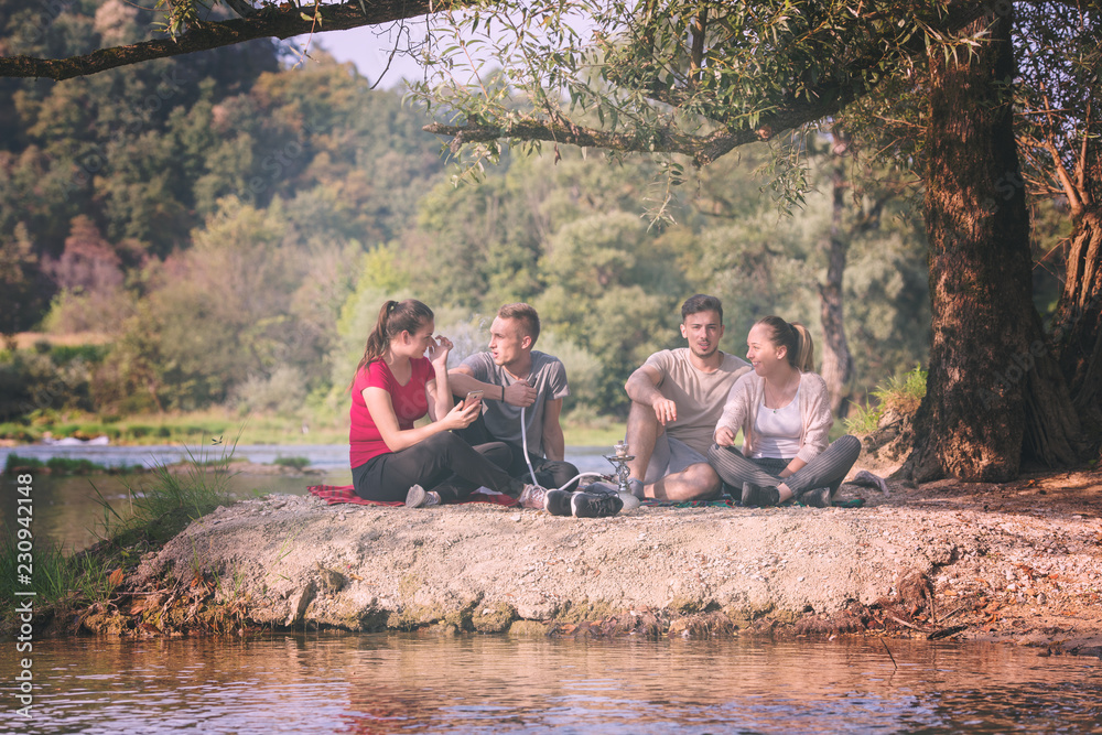 friends smoking hookah on the river bank friends smoking hookah on the river bank