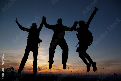 A group of tourists on top of a mountain at sunset.