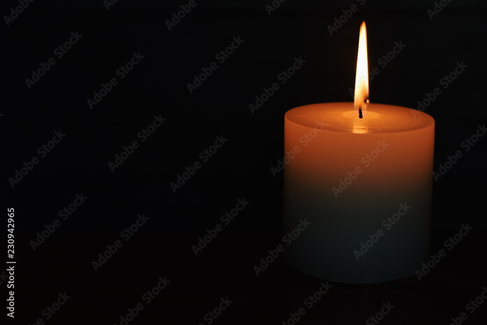 White burning candle on a dark background. Earth hour. White burning candle on a dark background. Earth hour.
