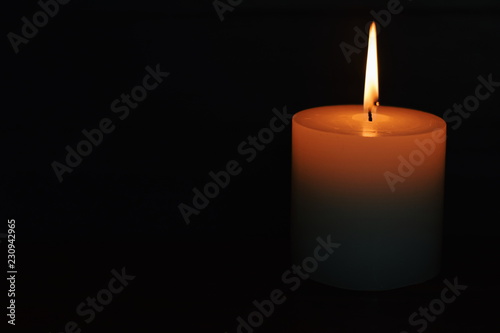 White burning candle on a dark background. Earth hour.