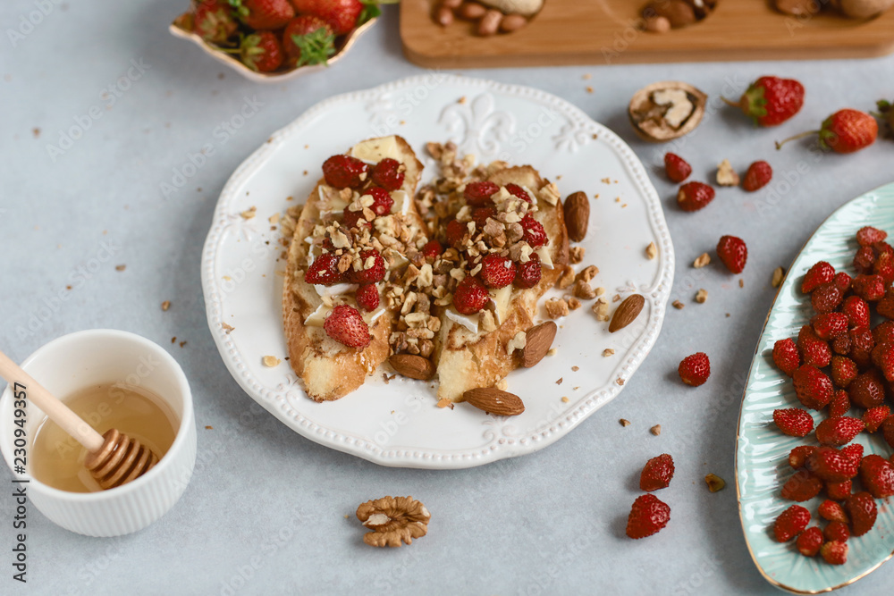 bruschetta with strawberries, cheese, camembert, brie, nuts and honey on the whole grain bread bruschetta, light background bruschetta with strawberries, cheese, camembert, brie, nuts and honey on the whole grain bread bruschetta, light background