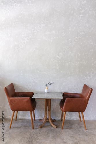 Brown leather armchairs and marble coffee table on gray fresco wall background in a restaurant