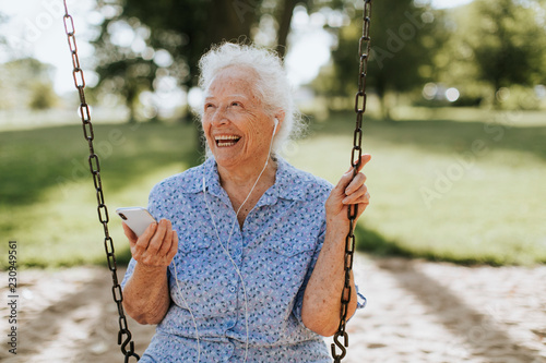 Cheerful senior woman listening to music at a playground photo