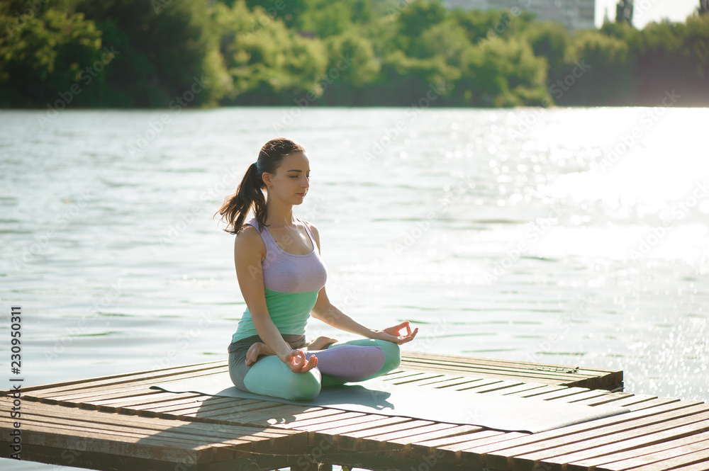 Young woman is practicing yoga at the lake