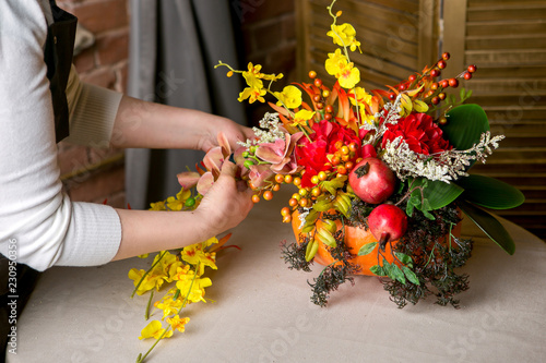 Foto Florist at work: How to make a Thanksgiving centerpiece with big pumpkin and bouquet of flowers