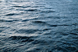 Restless water surface with ripples and light glares, may be used as background or texture