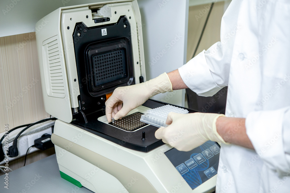 a laboratory specialist places test tubes with test samples in a special apparatus for studying the composition a laboratory specialist places test tubes with test samples in a special apparatus for studying the composition