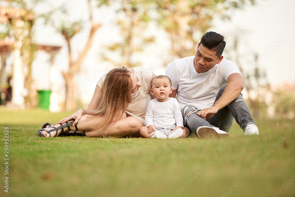 Young family with toddler boy having picnic in city park