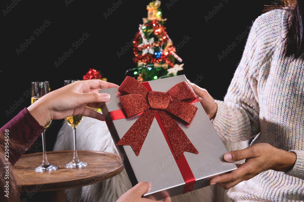 Beautiful two women holding gift boxes and two glasses with champagne celebrating Christmas at corporate party, New Year Frame for your text