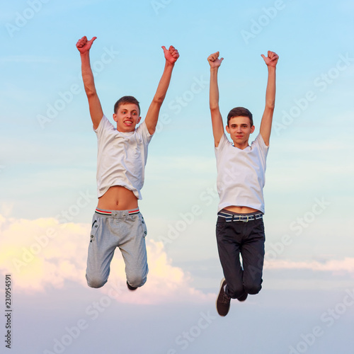 two happy young men jumping up on the nature