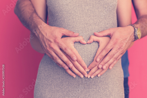 pregnant couple showing heart with their hands