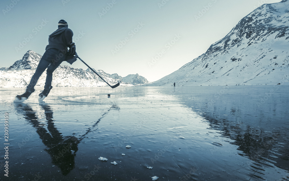 Beautiful view of the winter lake in the mountains. Clearing ice and winter  mood, ice hockey player with ice skating in nature on frozen lake Lago  Bianco - Switzerland Stock Photo