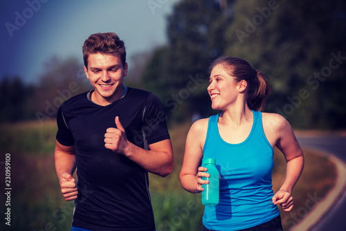 young couple jogging along a country road