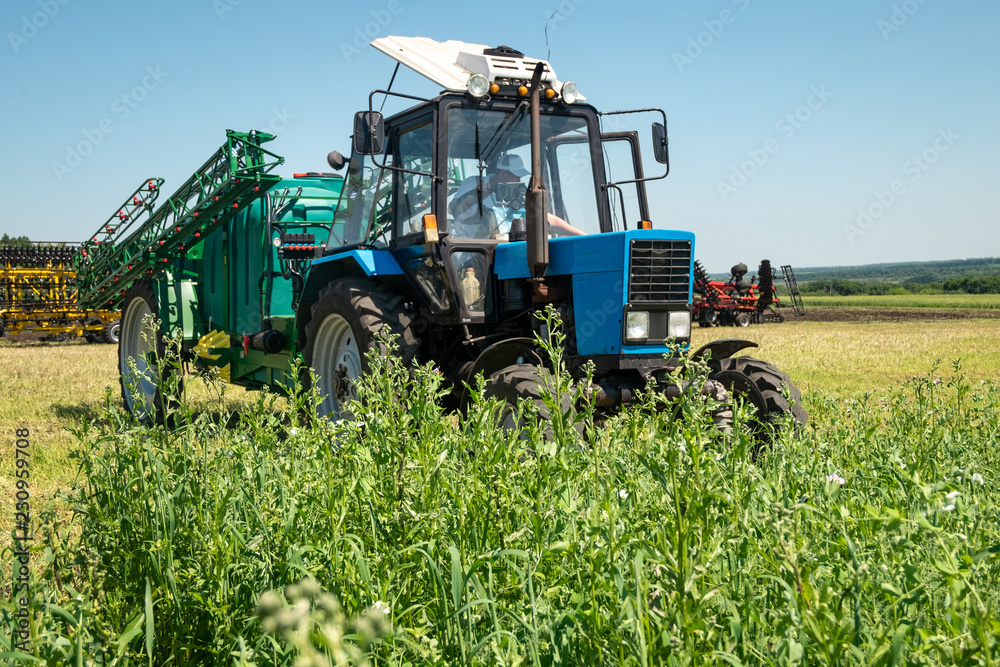 blue tractor in the field is preparing for chemical treatment of plants blue tractor in the field is preparing for chemical treatment of plants