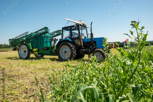 blue tractor in the field is preparing for chemical treatment of plants