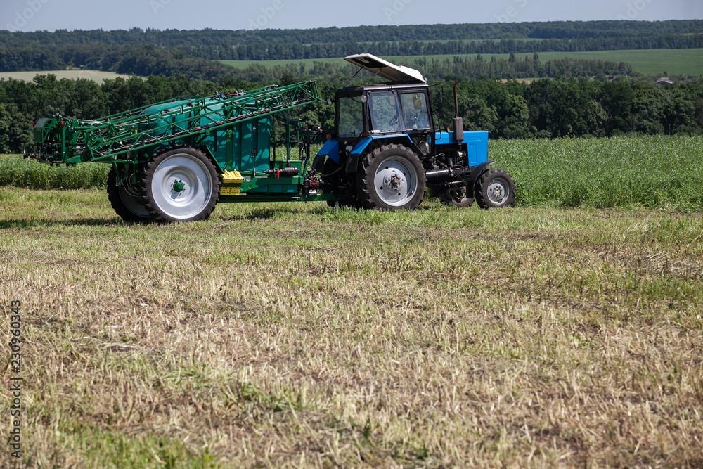 Fototapeta premium blue tractor in the field is preparing for chemical treatment of plants