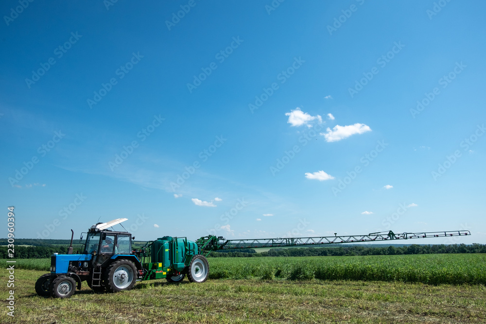 blue tractor in the field is preparing for chemical treatment of plants blue tractor in the field is preparing for chemical treatment of plants