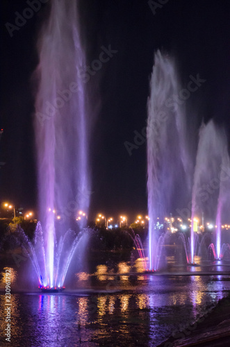 Colored luminous fountains in the middle of the lake at night.