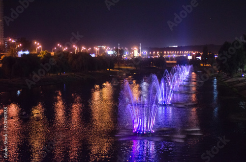 Colored luminous fountains in the middle of the lake at night.