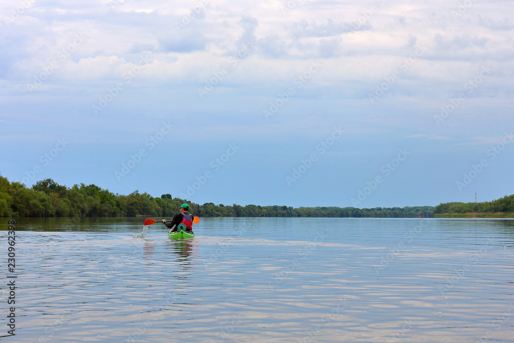 Man paddling in green kayak on a Danube river. Water tourism. Kayaking.