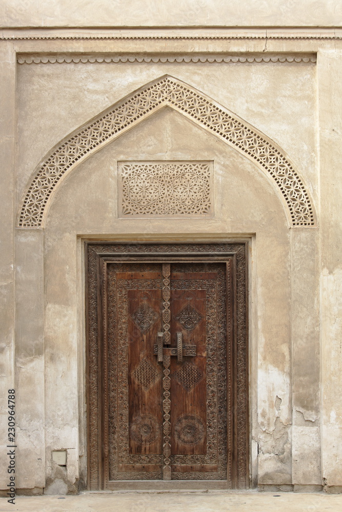 Carved wooden door and ornate doorway in a courtyard of traditional Arabian house of pearl trader Shaikh Isa bin Ali, Muharraq, Bahrain 