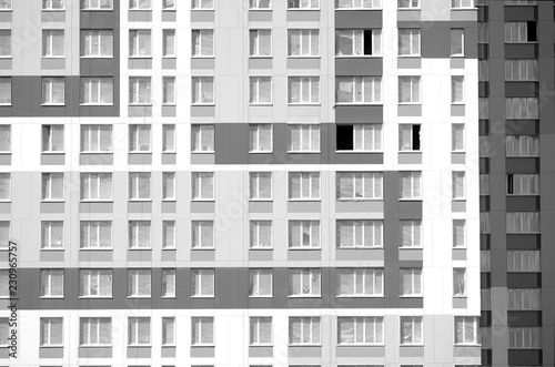 Modern new residential urban building with finished wall with many windows front view on sunny day closeup