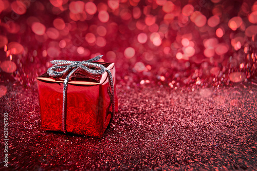 Red gift on blurred background. Christmas festive backdrop.