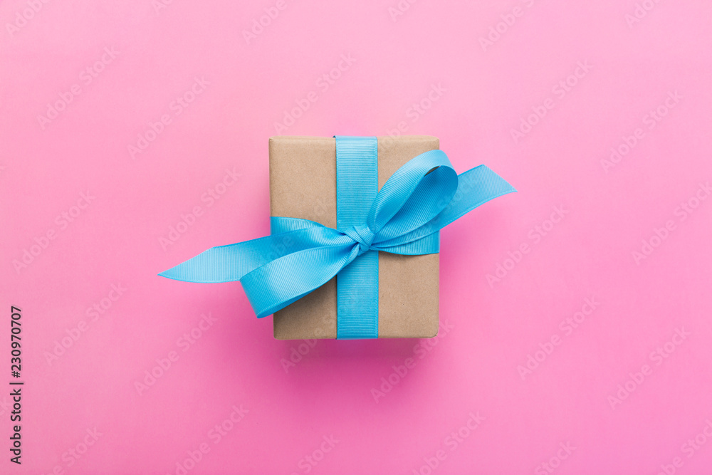 gift wrapped and decorated with blue bow on pink background with copy space. Flat lay, top view gift wrapped and decorated with blue bow on pink background with copy space. Flat lay, top view