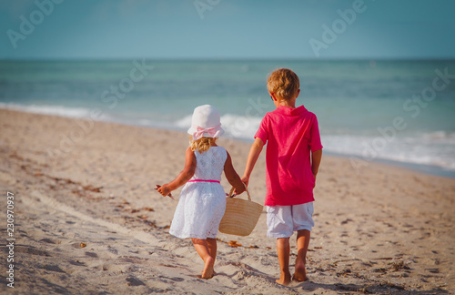 little boy and girl walk on summer beach