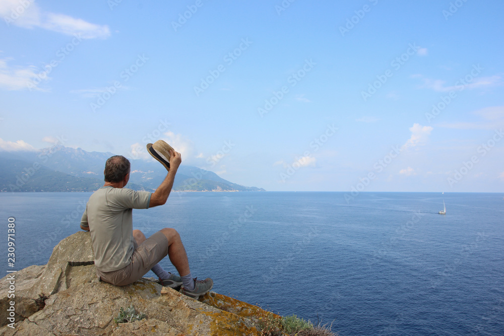 Man with straw hat enjoying the view in Elba island, Enfola headland, Italy