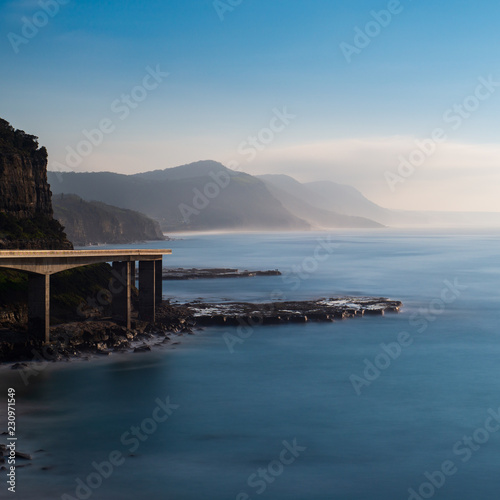 Sunrise over the Sea Cliff Bridge, Australia. Mountains of the Royal National Park in the background.. photo