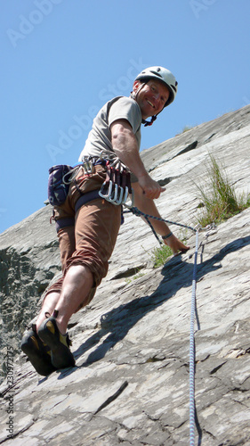 mountain guide rock climber on a slab limestone climbing route in the Alps of Switzerland on a beautiful day photo