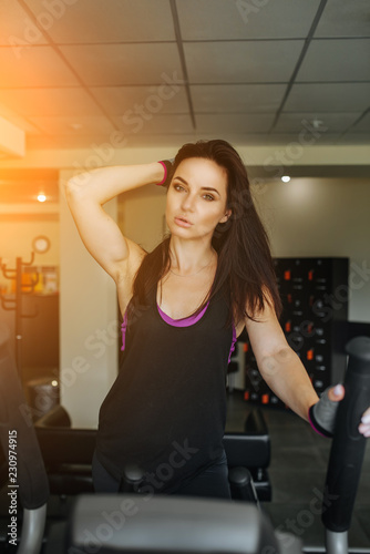 Fitness girl running on running machine or treadmill in fitness gym with sun ray. Gym exercising. Run on a machine. Healthy activity concept. Workout and strength training theme. © vitleo