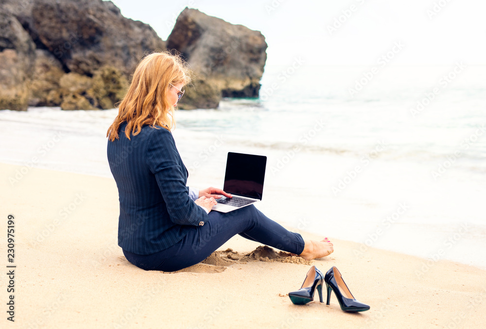 Business lady working with laptop computer on the beach