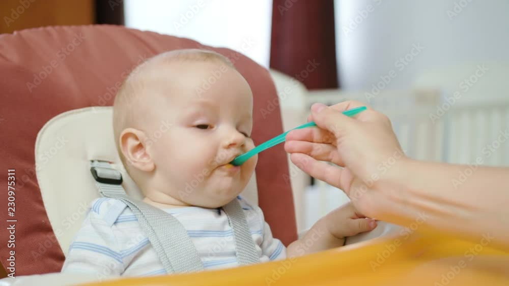 Cute baby eating in the babychair at home. Close-up shot Cute baby eating in the babychair at home. Close-up shot