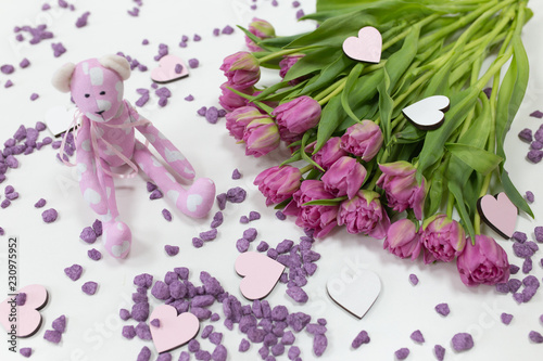 toy bear and fresh flowers of lilac color on a light background