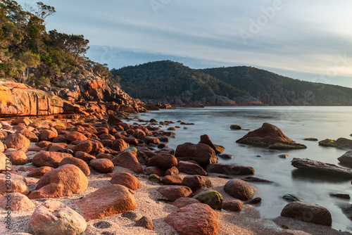 Sleepy Bay, Freycinet National Park, Tasmania. Sunrise over a rocky beach on a calm morning.